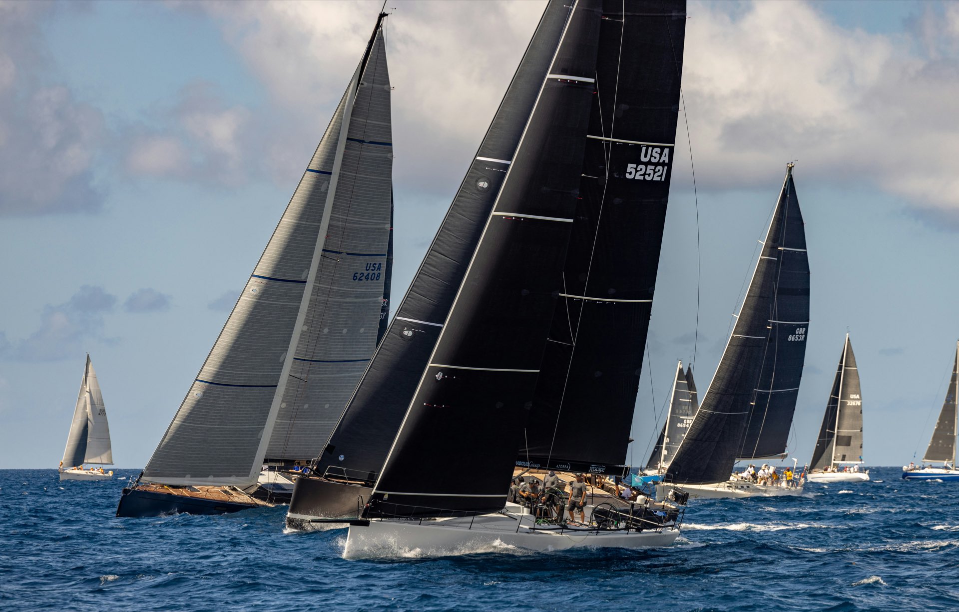 Black-sailed racing yachts close together at a start